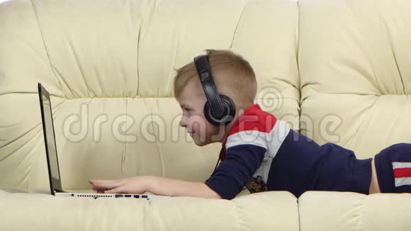 在沙发上手提电脑上玩网络游戏的男孩关门视频的预览图