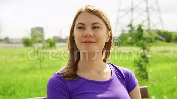 慢动作快乐微笑年轻女人享受自然坐在绿色公园的长凳上自由孤独概念视频的预览图