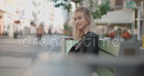 美丽的女人坐在长凳上等待约会视频的预览图