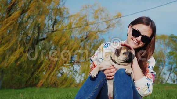 在公园里休息带着一只狗和零食去热狗一个年轻的女人坐在公园里的湖上玩她的球视频的预览图