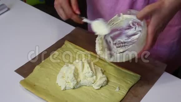 一个女人正在海绵蛋糕上撒奶油饼干卷的准备准备阶段视频的预览图