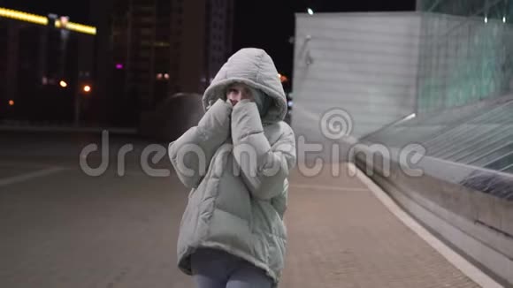 年轻漂亮的女人晚上在城市的广场上走来走去视频的预览图