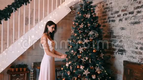 今年一个穿着浅色衣服的漂亮女孩装饰了一棵圣诞树视频的预览图