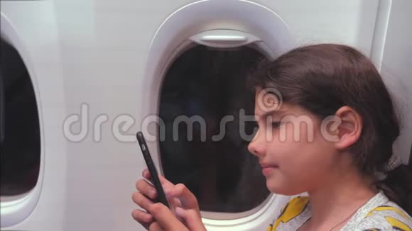 航空飞机概念年轻女孩正坐飞机在窗户旁边聊天看着生活方式视频的预览图