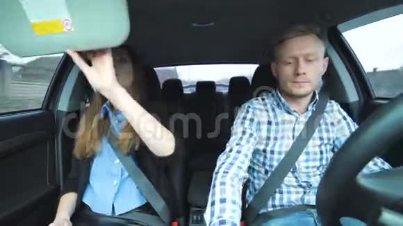 有趣的男人唱歌跳舞女孩在车上涂睫毛膏视频的预览图
