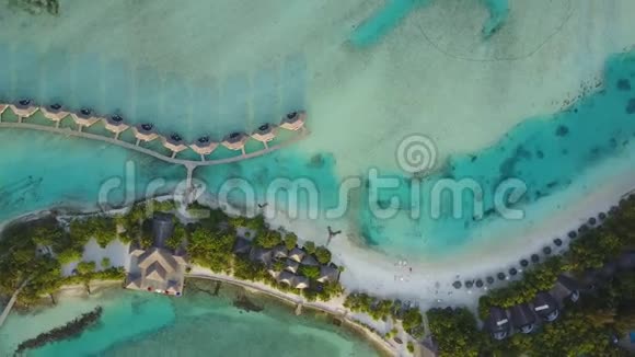空中无人机摄像机在热带岛屿上旋转白色沙滩和度假胜地有棕榈树的影子平房和视频的预览图