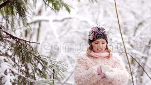快乐的女孩摇着森林里树枝上的雪快乐的童年冬季乐趣视频的预览图