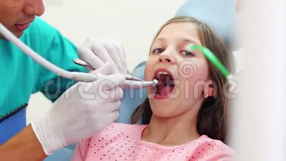牙医和助理修理可爱女孩的牙齿她竖起大拇指视频的预览图