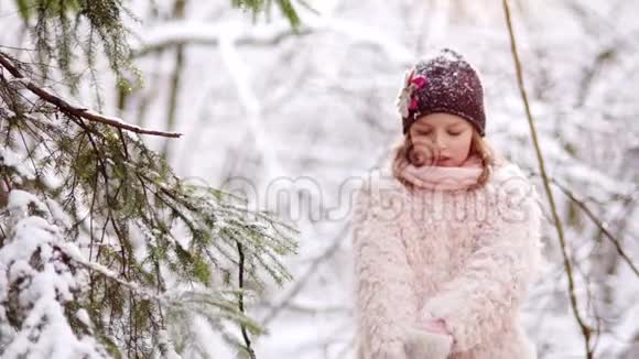 一个甜美的女孩从冬天的树枝上摇雪冬季运动会节日快乐圣诞节假期视频的预览图