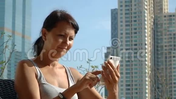 在摩天大楼背景下用电话微笑的女人视频的预览图