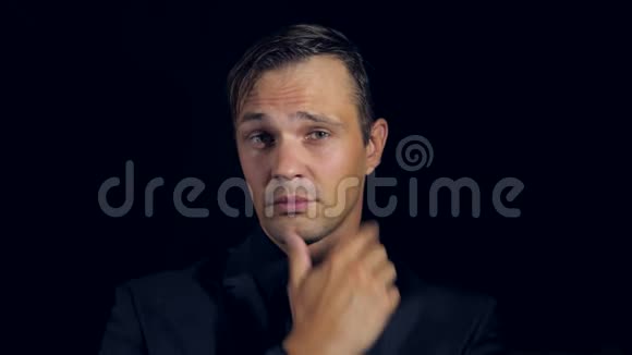 一个穿黑色衣服的人在黑色背景上的特写4k慢动作男人抚摸着下巴看着相机视频的预览图
