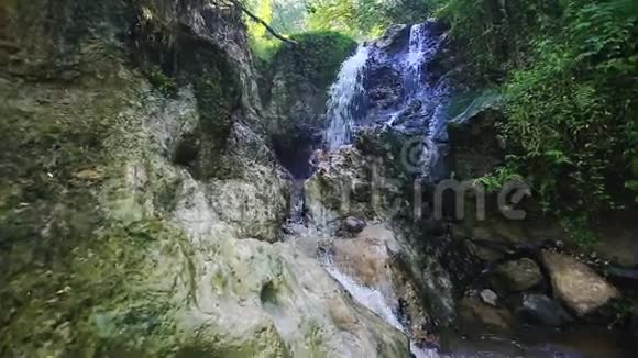 人类沐浴在岩石之间的强烈瀑布喷射下视频的预览图