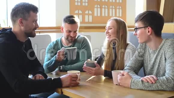 一群快乐的朋友或同事在一家小咖啡馆里喝着咖啡笑着一起用电脑视频的预览图