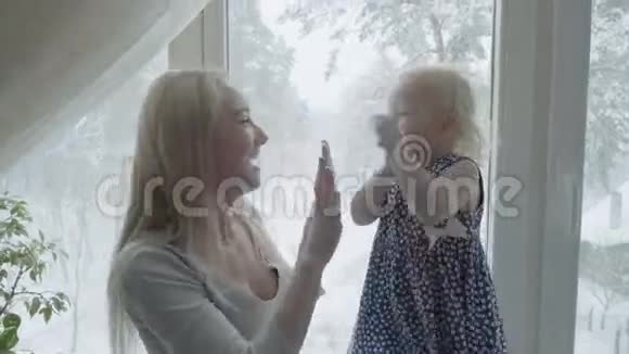 年轻的母亲和她的女儿正在靠窗玩耍视频的预览图