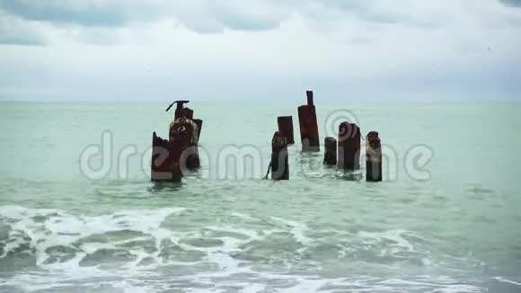 波浪在旧码头的水中的卵石滩上翻滚视频的预览图