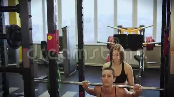 女子在健身俱乐部与教练一起增加肌肉质量视频的预览图