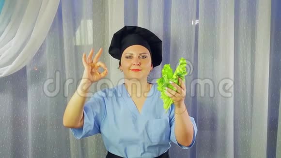 女人穿着围裙做饭微笑着手里拿着绿色沙拉举手好吗视频的预览图