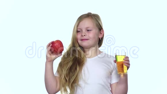 孩子从杯子里喝果汁拿着苹果白色背景慢动作视频的预览图