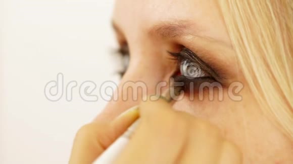 化妆师给模特的女孩投阴影靠近镜头傻眼的眼睛视频的预览图
