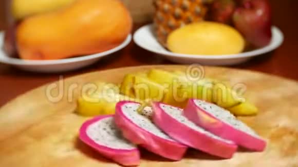 餐桌上的异国水果杨桃和龙果切成块在切割板上旋转视频的预览图