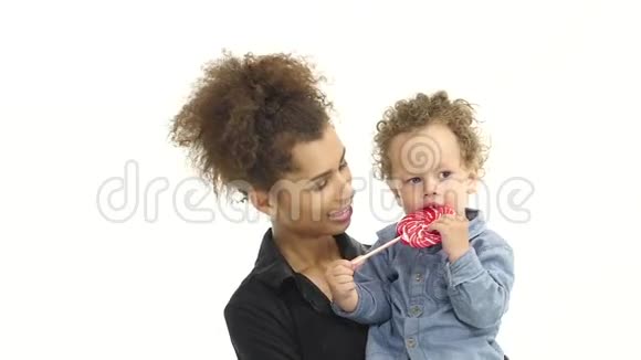 非裔美国母亲抱着一个儿子舔着一颗糖果亲吻着一个婴儿白色背景慢动作视频的预览图