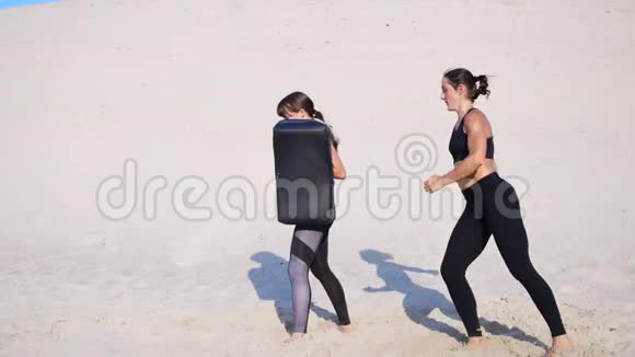 两个穿着黑色健身服的年轻女子参加了一对锻炼踢腿训练蹲和踢腿视频的预览图