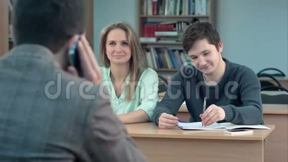 一群大学生坐在礼堂的课桌前等着老师而他正在谈论视频的预览图