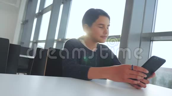 十几岁的女孩在聊天在生活方式中交流信使在智能手机桌子阳光下的咖啡馆里智能手机里的信使视频的预览图