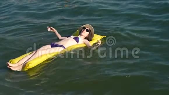 在沙滩上充气床垫上放松的女人视频的预览图