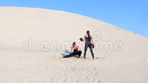 两个穿着黑色健身服的年轻女子参加了一对锻炼踢腿训练蹲和踢腿视频的预览图