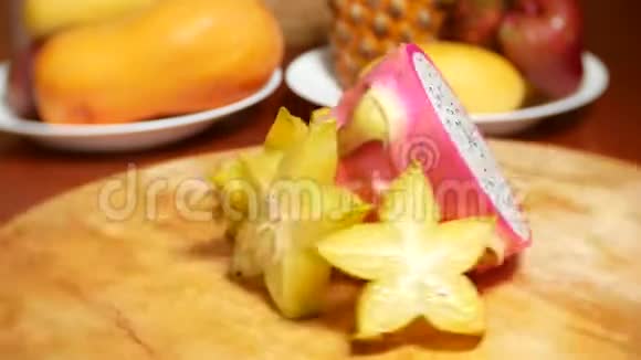 餐桌上的异国水果杨桃和龙果切成块在切割板上旋转视频的预览图