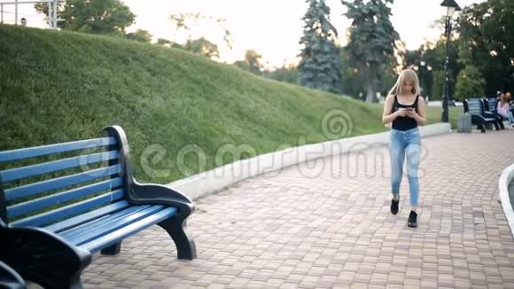 女人在公园散步看着智能手机感到不舒服她的脚停下来坐在长凳上视频的预览图