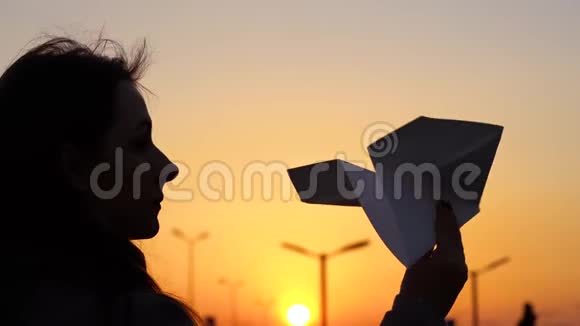 女人在日落的背景下发射纸飞机想去度假或旅行的概念慢动作视频的预览图