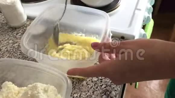 一个女人在一个容器里加入了干酪里面有融化的黄油香草和糖粉甜点的配料视频的预览图