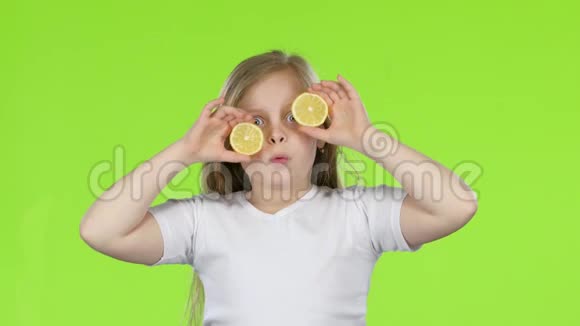 小女孩用柠檬闭上眼睛表现出不同的情绪舔它和呱呱叫绿色屏幕视频的预览图
