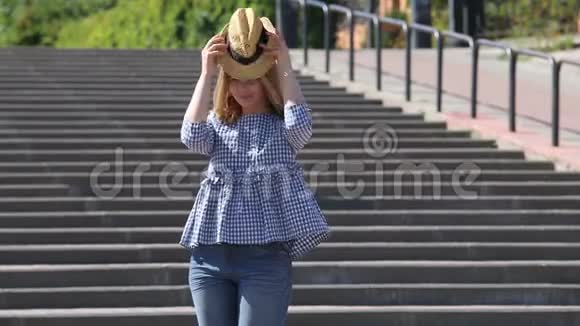 城市楼梯上漂亮的金发女郎戴上草帽飞吻视频的预览图