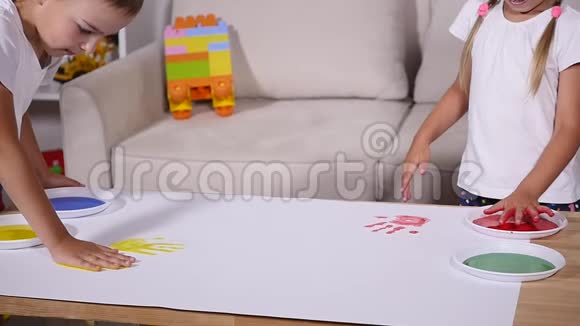 一个女孩和一个男孩在纸上留下手印动作缓慢视频的预览图