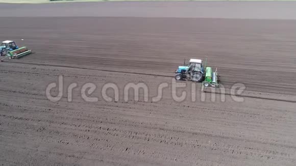 两辆拖拉机一辆接一辆穿过田野的鸟瞰图视频的预览图