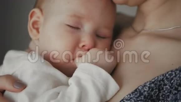年轻的母亲抱着她的新生儿熟睡的孩子家庭视频的预览图