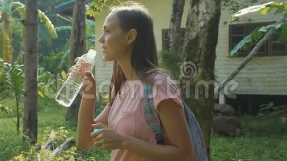 年轻女子站在亚细亚村的乡间小路上喝着水视频的预览图