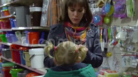 一个年轻的女人带着一个孩子在超市选择商品妈妈在手推车上驾驶一个小女孩考虑一下货物视频的预览图