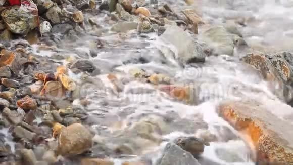 卵石海滩小卵石和海浪日落时波浪沿着岩石海岸奔流视频的预览图