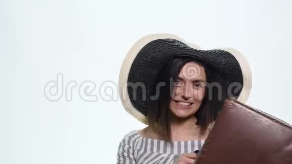 戴柳条帽提着手提箱拿着护照带着白色车票的时髦年轻女性肖像视频的预览图
