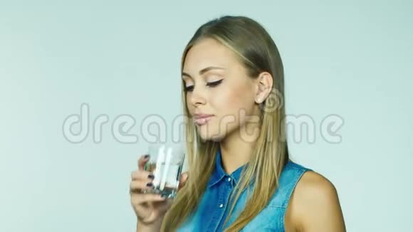漂亮的金发女郎用白底玻璃杯喝水视频的预览图