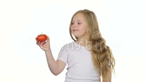 小女孩看着一个西红柿欣赏它竖起大拇指白色背景视频的预览图