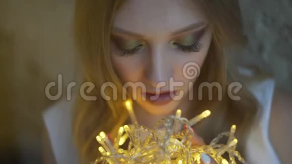 美丽少女靠墙少女手持花环圣诞灯视频的预览图