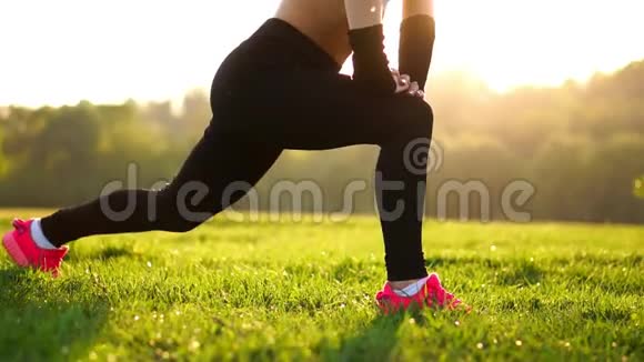 苗条的女运动员在公园里锻炼做膝盖弹跳或弓箭步穿着粉色运动鞋的日落脚视频的预览图