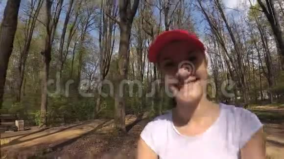快乐开朗微笑的年轻女子在阳光明媚的公园里的树下骑自行车POV行动摄影机视频的预览图