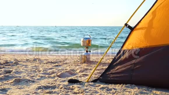 日出时在沙滩上的帐篷附近用烹饪锅做露营炉子视频的预览图