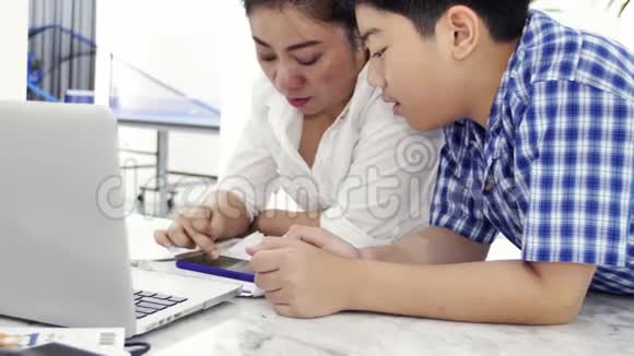母亲和儿子玩和看智能手机多莉拍摄了快乐的亚洲家庭在家的笑脸视频的预览图